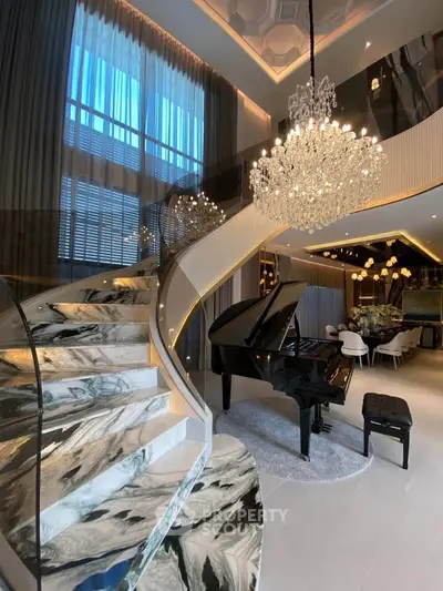 Luxurious living room with grand piano and elegant staircase under a stunning chandelier.