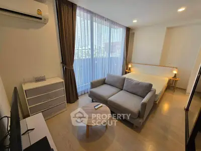 Modern studio apartment with cozy living area and large window view.