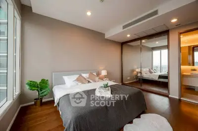 Luxurious bedroom with mirrored closet and city view, featuring elegant decor and cozy ambiance.