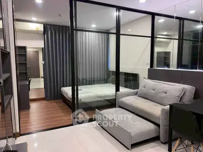 Modern studio apartment with glass partition, cozy living area, and sleek bedroom design.