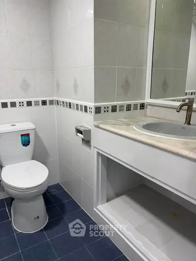 Modern bathroom with sleek fixtures and tiled walls, featuring a toilet and a stylish sink area.