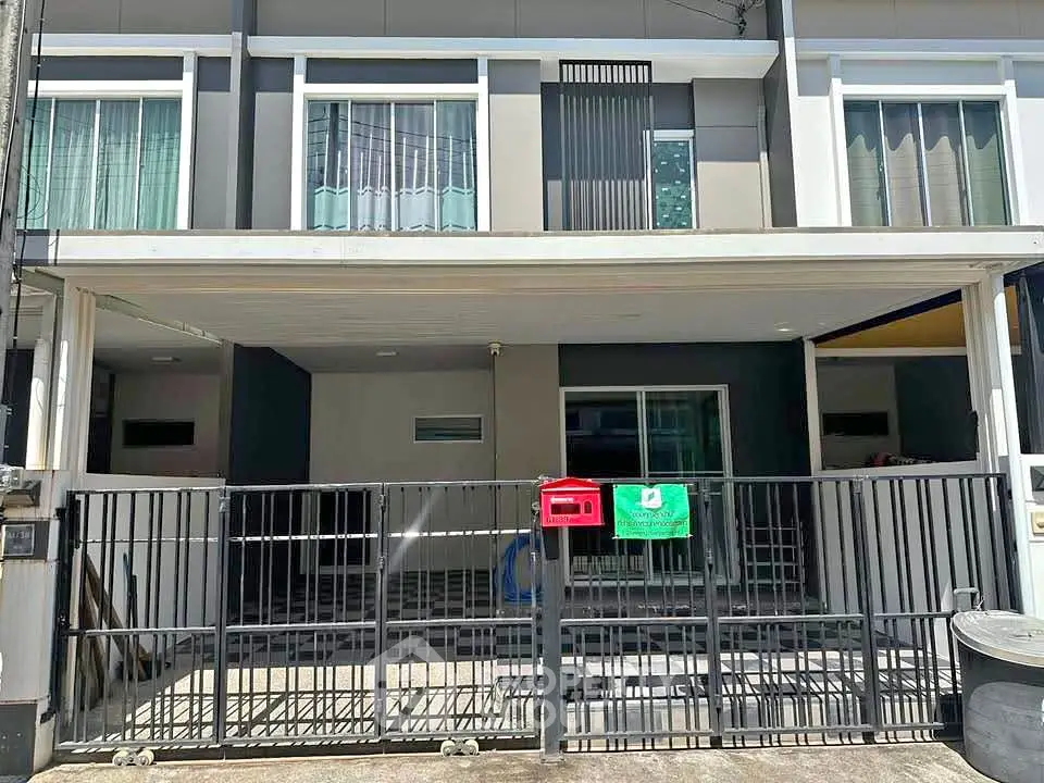 Modern townhouse exterior with gated parking area and contemporary design.