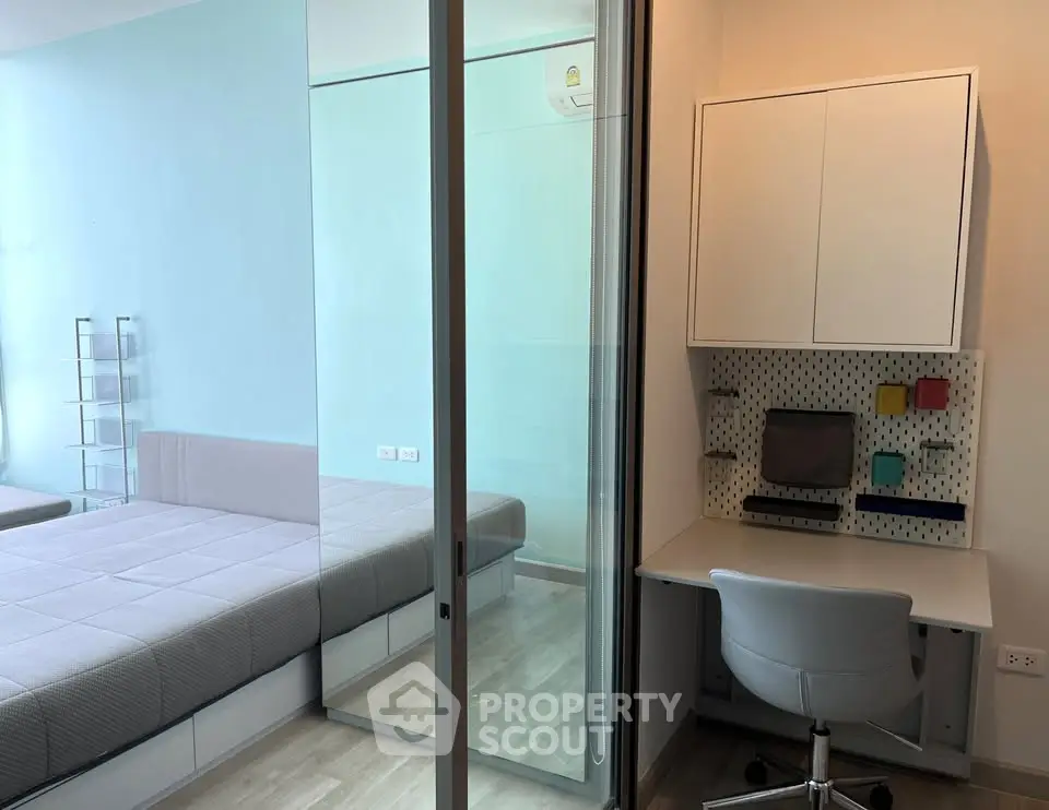 Modern bedroom with glass partition and study area, featuring sleek furniture and minimalist design.