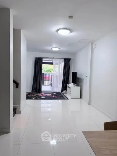 Spacious modern living room with glossy white tiles and large window for natural light.