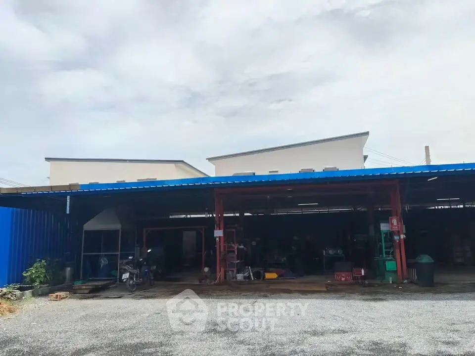 Industrial warehouse exterior with spacious parking area and metal roofing.