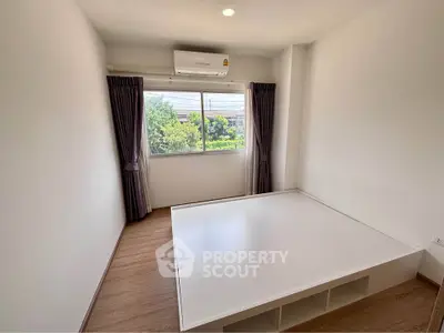 Spacious bedroom with large window and built-in storage bed, featuring natural light and modern design.