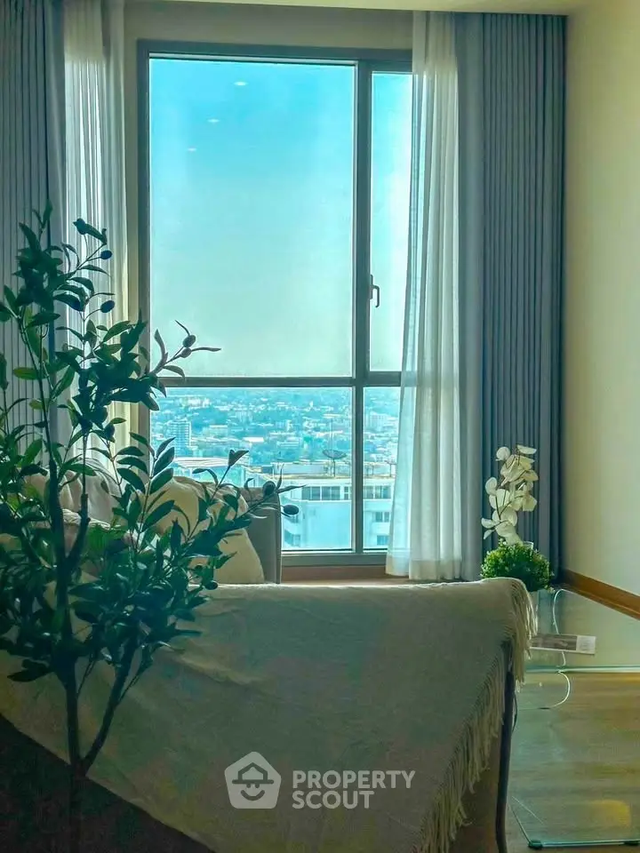 Bright living room with large window offering stunning city view and elegant decor.