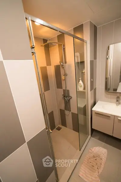 Modern bathroom with glass shower enclosure and sleek vanity unit.