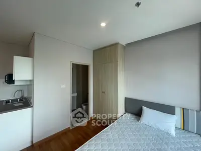 Modern bedroom with integrated kitchenette and ensuite bathroom in a stylish apartment.