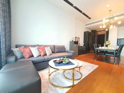 Spacious modern living room with elegant decor and dining area, featuring stylish furniture and warm lighting.
