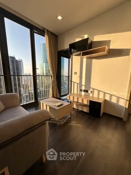 Modern living room with city view, featuring sleek furniture and floor-to-ceiling windows.