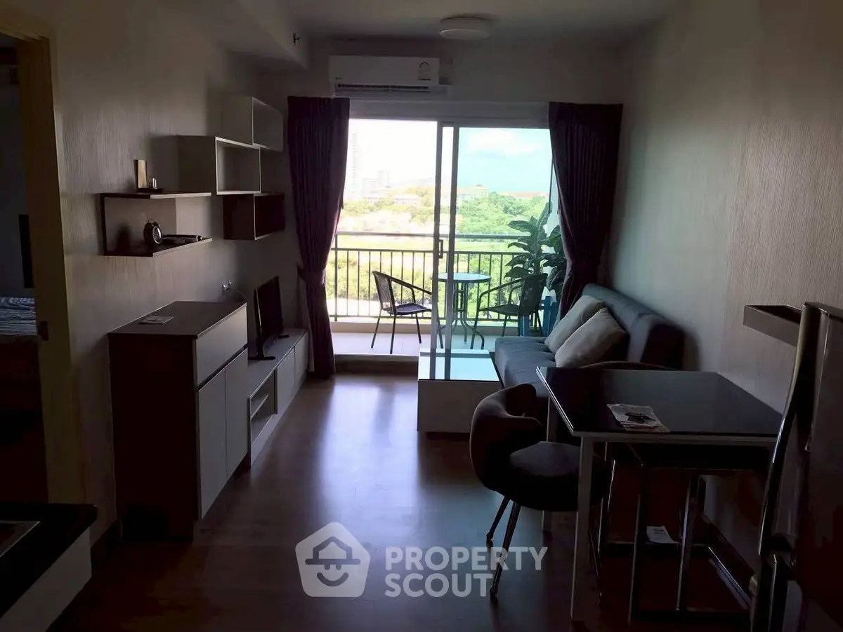 Modern living room with balcony and scenic view, featuring sleek furniture and ample natural light.