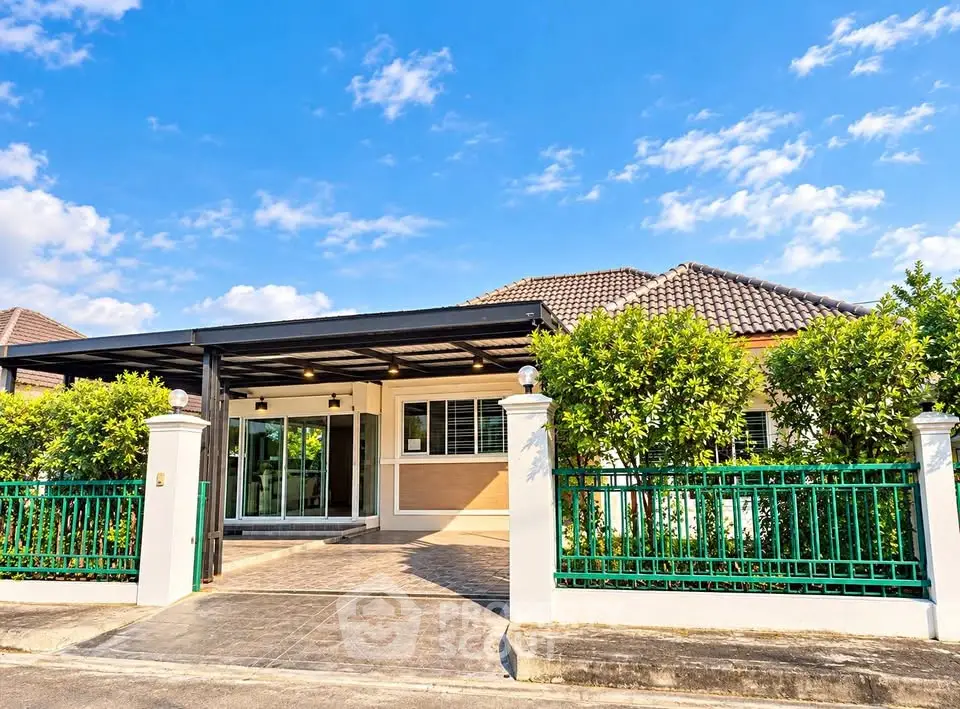 Charming single-story house with lush greenery and spacious driveway under a clear blue sky.
