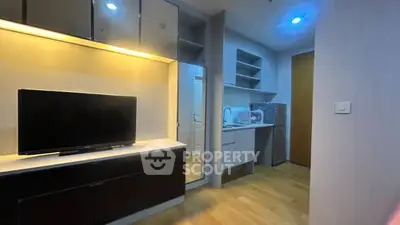 Modern apartment interior with sleek TV unit and compact kitchen area.