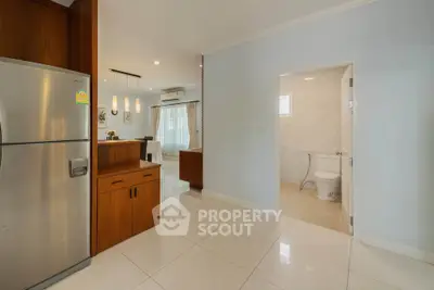 Modern open-plan kitchen and dining area with adjacent bathroom, featuring sleek appliances and elegant lighting.