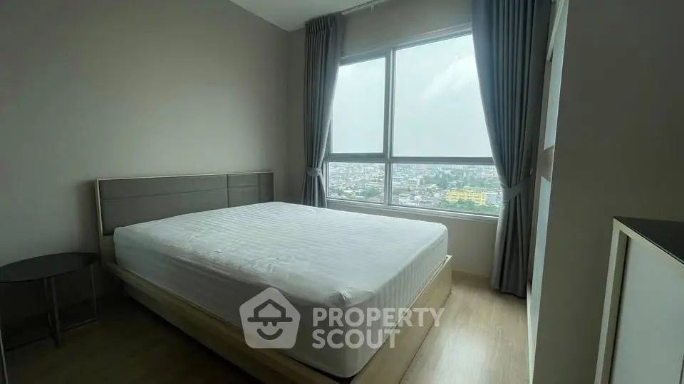 Spacious bedroom with large window offering stunning city views, perfect for urban living.