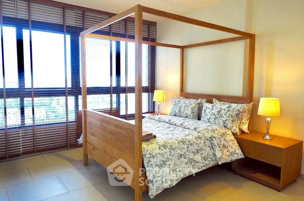 Spacious bedroom with elegant wooden bed and large windows offering natural light.