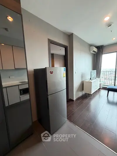 Modern apartment interior with sleek kitchen and spacious living area featuring large windows.