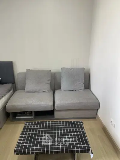Modern living room with stylish gray sofa and checkered coffee table in cozy apartment.