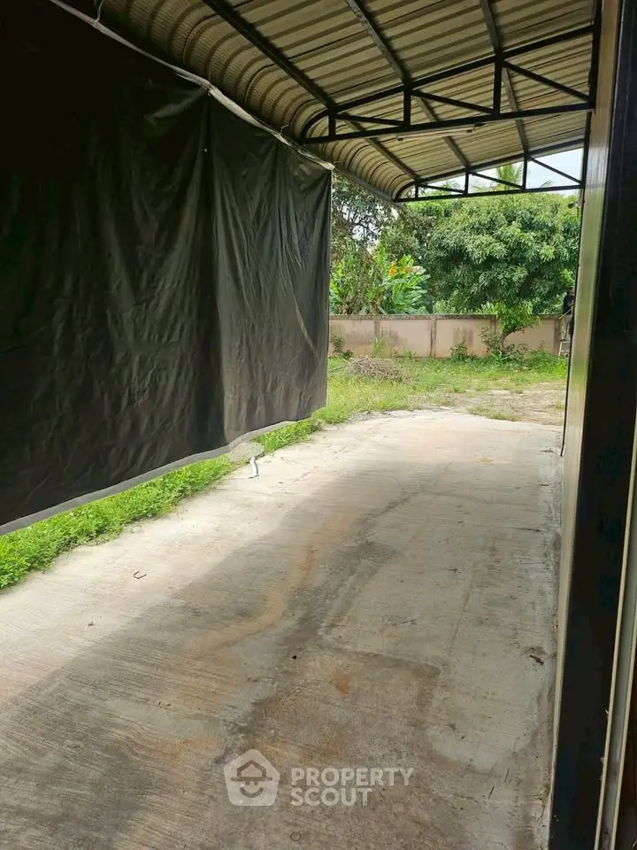 Spacious covered parking area with lush greenery and privacy wall