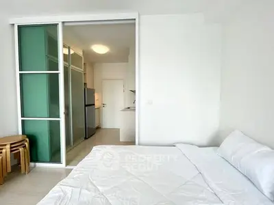 Modern studio apartment with sliding glass doors and compact kitchen.