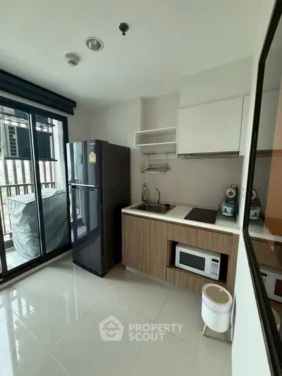 Modern kitchen with sleek appliances and balcony view in urban apartment