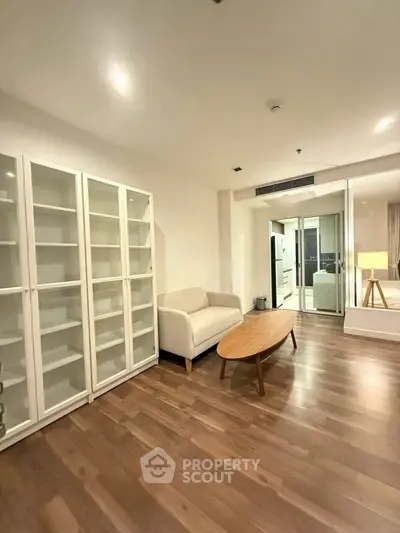 Spacious living room with wooden flooring and modern furniture in a stylish apartment.