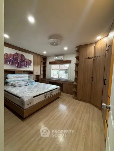 Spacious bedroom with modern wooden cabinetry and large window view