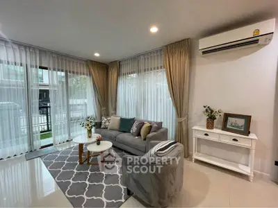 Elegant living room with modern decor, featuring a cozy sofa, stylish rug, and large windows with sheer curtains.