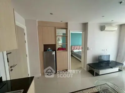 Modern apartment interior with open layout, featuring a cozy living area and a glimpse of the bedroom.