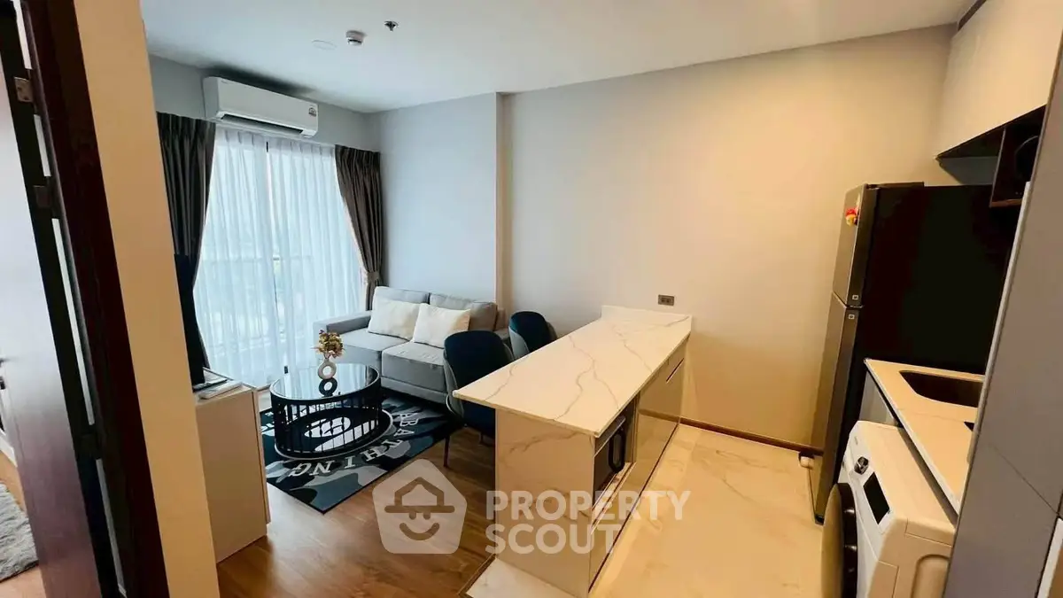 Modern open-layout living room and kitchen with stylish decor and natural light.