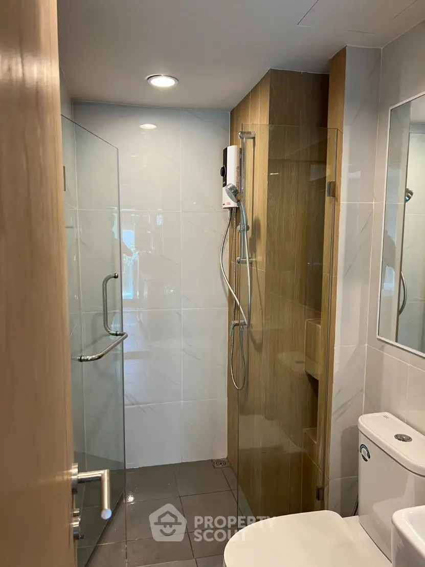 Modern bathroom with glass shower and sleek fixtures in contemporary apartment.