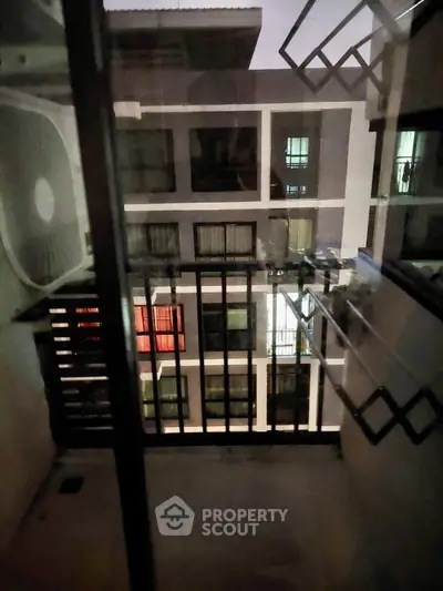 Modern apartment building view from balcony with air conditioning unit and drying racks.