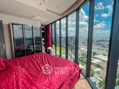 Luxurious bedroom with floor-to-ceiling windows offering stunning city views and elegant red bedding.
