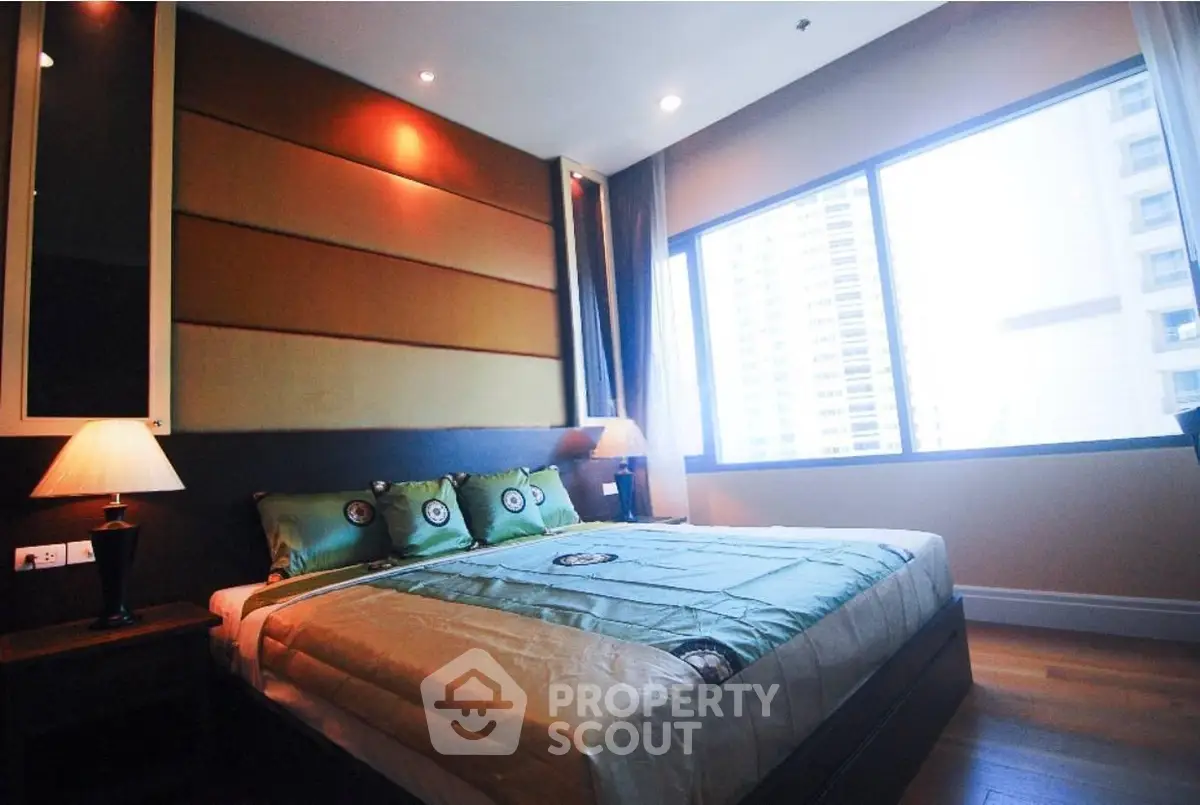 Luxurious bedroom with large window and modern decor in high-rise apartment.