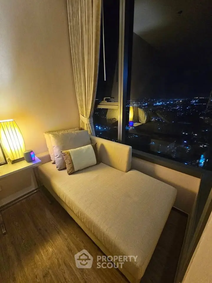 Cozy corner unit with night city view, featuring elegant chaise lounge and ambient lighting.