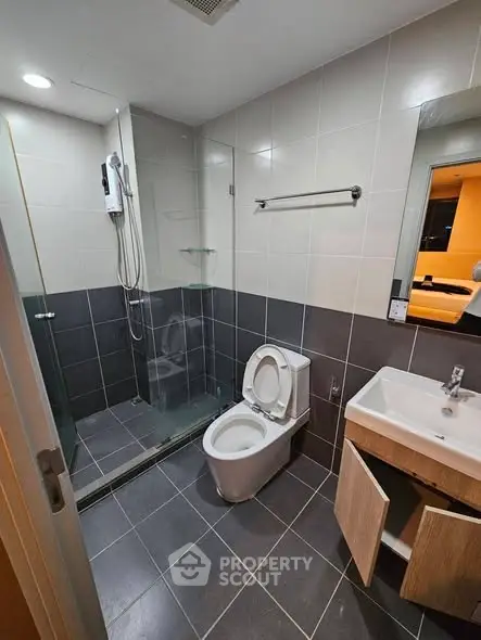 Modern bathroom with glass shower and sleek fixtures in contemporary apartment.