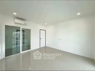 Spacious modern living room with sleek tile flooring and large glass doors.