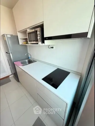 Modern kitchen with sleek cabinetry, built-in microwave, and induction cooktop in a compact layout.