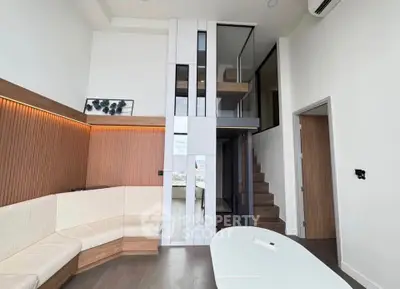 Modern living room with high ceiling and stylish wooden accents, featuring a mezzanine and sleek design.