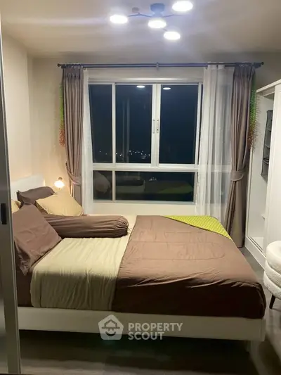 Cozy bedroom with modern decor and large window offering a serene night view.