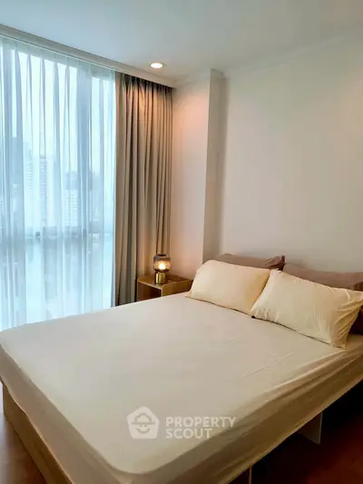 Modern bedroom with large window and stylish decor in urban apartment.