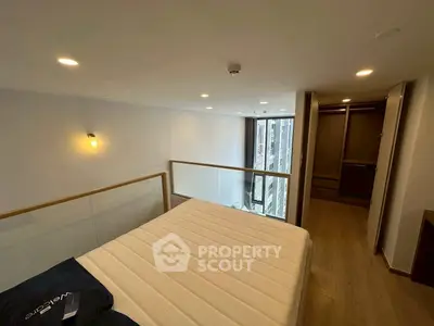 Modern loft bedroom with wooden flooring and large window offering city view.