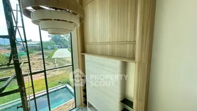Luxurious modern living room with high ceilings and large windows overlooking a pool and garden.