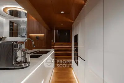 Luxurious modern kitchen with sleek white cabinetry and wooden accents, featuring high-end appliances and elegant lighting.