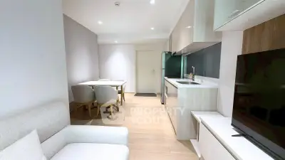 Modern living room with open kitchen and dining area, featuring sleek design and neutral tones.