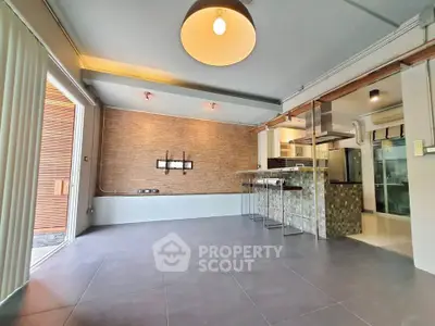 Modern open-plan living room with stylish kitchen and large windows for natural light.