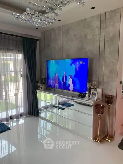 Luxurious living room with modern decor, large TV, and elegant chandelier, perfect for stylish living.