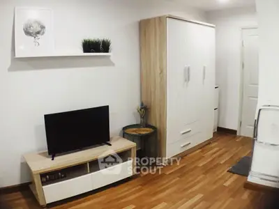 Modern living room with wooden flooring, TV stand, and wardrobe in a cozy apartment.
