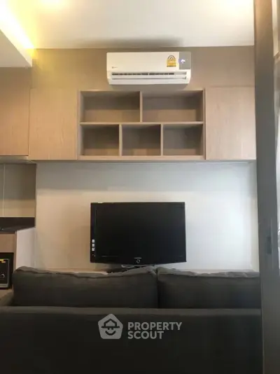 Modern living room with air conditioning and wall-mounted TV, featuring sleek wooden cabinetry.